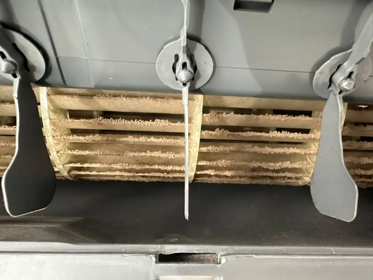 Aircon blower wheel seen through the outlet, blades thickly coated in dust