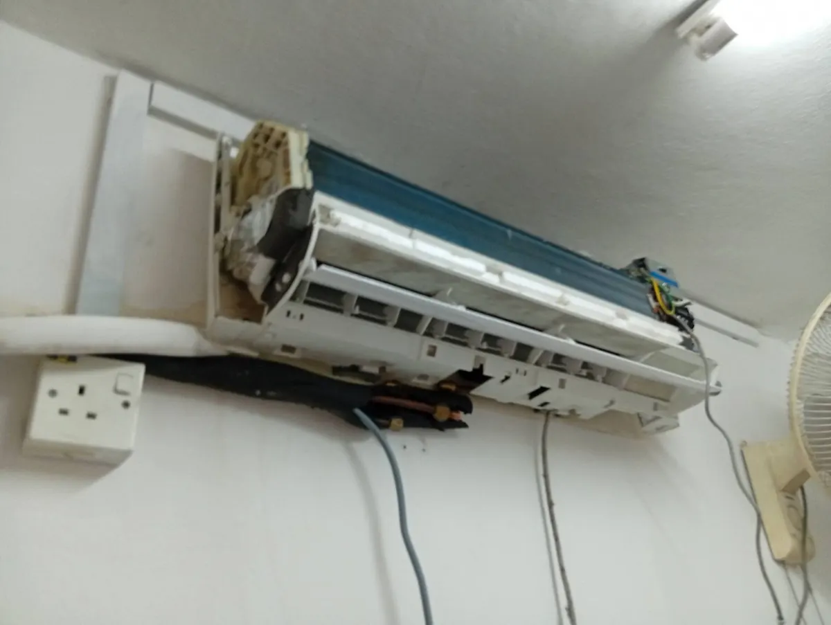 Wall-mounted aircon opened up with the drain pan tray removed for replacement